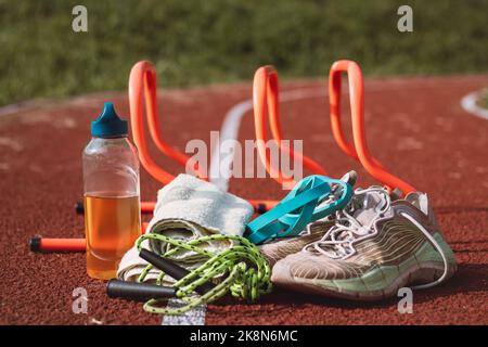 Équipement sportif pour une formation de qualité et un plaisir suffisants. Terrain de jeux sportif en plein air. Style de vie du jeu. Serviette, corde à sauter, t-shirt, haies, serviette et dri Banque D'Images