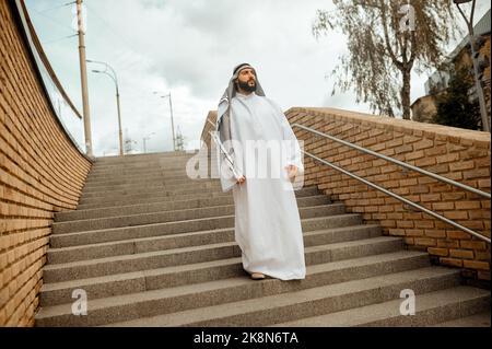 Un homme arabe en vêtements blancs traditionnels sur les escaliers Banque D'Images