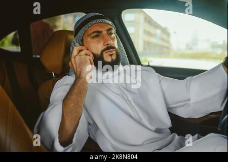 Saoudien assis dans une voiture et parlant au téléphone Banque D'Images