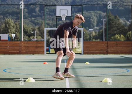 un joueur de hockey actif se prépare pour la saison de plein air. L'athlète blond pousse entre les cônes et ralentit son mouvement. Force de freinage appliquée à Banque D'Images