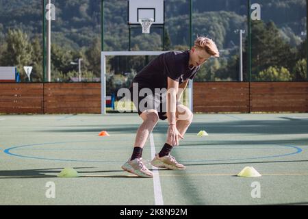 un joueur de hockey actif se prépare pour la saison de plein air. L'athlète blond pousse entre les cônes et ralentit son mouvement. Force de freinage appliquée à Banque D'Images