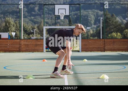 un joueur de hockey actif se prépare pour la saison de plein air. L'athlète blond pousse entre les cônes et ralentit son mouvement. Force de freinage appliquée à Banque D'Images