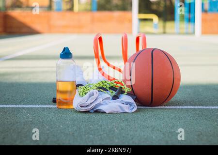 Équipement sportif pour une formation de qualité et un plaisir suffisants. Terrain de jeux sportif en plein air. Style de vie du jeu. Serviette, basket-ball, corde à sauter, t-shirt, serviette et Banque D'Images