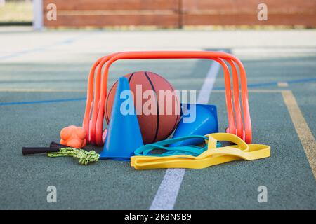 Équipement sportif pour une formation de qualité et un plaisir suffisants. Basket-ball, corde à sauter, haies, cônes bleus, élastiques, expandeurs. Jeux de sport en extérieur Banque D'Images
