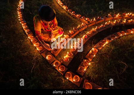 Narayanganj, Dhaka, Bangladesh. 24th octobre 2022. Les dévotés hindous illuminent « Diyas » (lampes en terre) sur un Rangoli, un cadre de motifs décorés, dans le cadre des festivités de Diwali dans un temple de Narayanganj, au Bangladesh. De nombreuses lampes à huile légères ou bougies symbolisent une victoire de la lumière sur l'obscurité, et les feux d'artifice sont mis en place dans le cadre des célébrations. Le festival a lieu chaque année conformément au calendrier lunaire hindou. Crédit : ZUMA Press, Inc./Alay Live News Banque D'Images