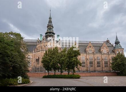 Suède, Stockholm - 16 juillet 2022 : façade arrière et tour du Nordiska Museet, musée d'histoire sous ciel gris. Feuillage vert et route Banque D'Images