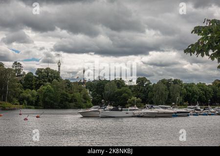 Suède, Stockholm - 16 juillet 2022: Djurgårdsbrunnsvikens Motorbåtsklubb avec des yachts blancs le long de la jetée sous couvert de nuages gris. Ceinture verte. Banque D'Images