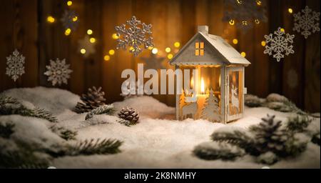 Scène de Noël avec lanterne et ornements suspendus, fond de bois et neige, la bougie en feu et les planches brunes créent une ambiance chaleureuse et chaleureuse Banque D'Images