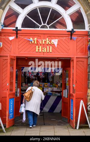 Richmond, Yorkshire du Nord, Royaume-Uni - 3 août 2020 : une femme traverse l'entrée du marché intérieur de Richmond Banque D'Images