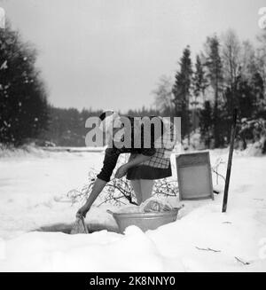 Hedmark à l'hiver 1948. Pénuries d'eau dans l'est de la Norvège après la sécheresse de l'été 1947. Les fermes doivent aller chercher de l'eau dans les rivières ou s'assurer que l'eau coule des laiteries. Ici, une femme lave les vêtements dans un ruisseau, à travers un trou qui est haché dans la glace. BALLE avec vêtements et planche à laver. Photo: Børretzen / courant / NTB Banque D'Images