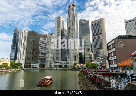 Singapour emblématique. Boat Quay pris en fin d'après-midi, avec le quartier financier de Singapour en arrière-plan et un bateau touristique passant Banque D'Images