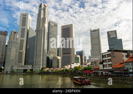 Singapour emblématique. Boat Quay pris en fin d'après-midi, avec le quartier financier de Singapour en arrière-plan et un bateau touristique passant Banque D'Images