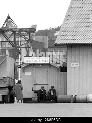 Oslo à l'été 1962. Une promenade le long de l'Akerselva de OS à OS. Au hangar n° 60 de Pedersen et Meinich sur le quai à 'Køla-Pålsen' (officiellement Paulsenkaia), deux travailleurs ont trouvé un endroit où ils peuvent manger la boîte à lunch et partager une bouteille, et ils sont heureux de partager une dame qui passe aussi .. Photo: Åge Storløkken / actuel / NTB. Lok physique: Actuel 1962 No. 37: Akerselva, vous avez vieux vous gris. Banque D'Images