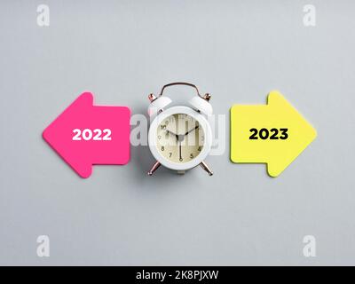 L'année 2022 et 2023 écrit sur des papiers de note de flèche à côté d'une horloge. Planification du nouveau concept de l'an 2023. Banque D'Images