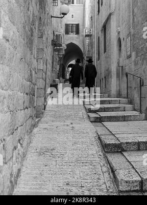 Photo en niveaux de gris de deux hommes juifs qui marchent dans les rues étroites du quartier juif Banque D'Images