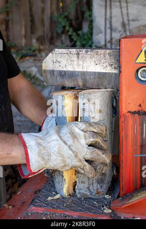 Homme fendant le bois avec la machine hydraulique de séparation de grumes Banque D'Images