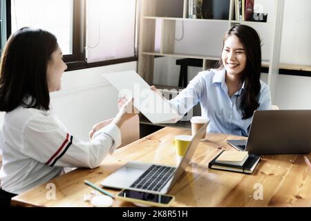 Deux employées de l'entreprise se soumirent avec joie les unes des autres en se remant les dossiers. Banque D'Images