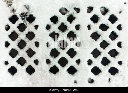 texture d'une grille d'égout pluvial recouverte de neige. Arrière-plan abstrait Banque D'Images