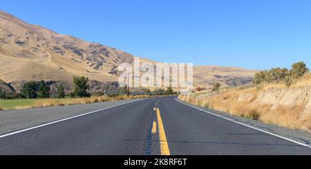 State route 821 en passant par le Yakima Canyon dans l'État de Washington central avec route passant par des collines arides et occasionnellement des terres agricoles Banque D'Images