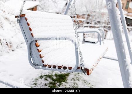 Balançoire blanche en bois recouverte de neige après une forte neige. Hiver givré jour Banque D'Images