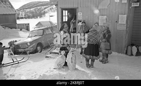 Finnmark 19650410 pris par Finnmarksvidda - l'une des nouvelles de cette année est les voyages d'hiver à Finnmarksvidda. Aussi sans le soleil de minuit, la région a beaucoup à offrir aux touristes: Rencontre avec Sami et renne, ski magnifique et paysage magnifique. C'est Bennett Reiseburå qui organise les voyages au nord. Les billets au prix de NOK. 1295,- pour un voyage de 9 jours, tout compris, a été arraché. Ici: Femmes et hommes à l'extérieur des maisons en bois. Voiture garée. Photo: Aage Storløkken / actuel / NTB Banque D'Images