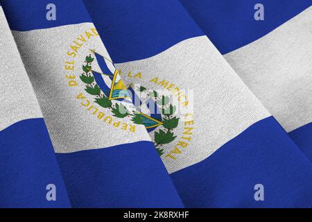 Drapeau El Salvador avec de grands plis et un gros plan sous la lumière du studio à l'intérieur. Les symboles officiels et les couleurs de la bannière en tissu Banque D'Images