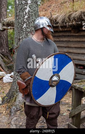 Reacteur barbu portant un casque de combat, une armure de courrier en chaîne et un bouclier en bois lors de la reconstitution du marché de l'âge de fer de Pukkisaari à Helsinki, en Finlande Banque D'Images