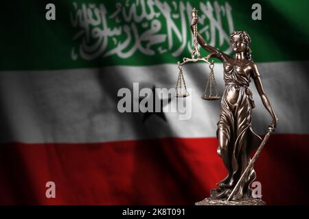 Drapeau du Somaliland avec statue de la justice des femmes et balance judiciaire dans la pièce sombre. Concept de jugement et de punition, contexte des sujets de jury Banque D'Images