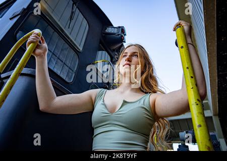 Jeune femme debout sur l'escalier d'un moteur électrique diesel de train Banque D'Images