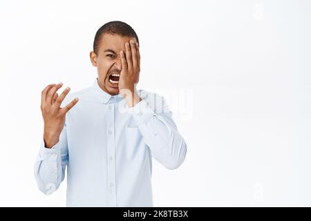 Homme en colère fuyant la rage, criant et hurlant indigné, debout sur fond blanc Banque D'Images