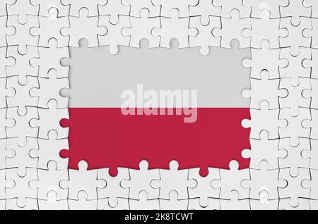 Drapeau polonais dans le cadre de pièces de puzzle blanc avec des pièces centrales manquantes Banque D'Images