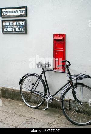 Un cliché vertical d'un vieux vélo stationné à côté d'une boîte à poste Banque D'Images