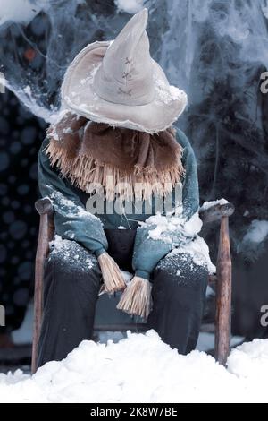 Halloween décoration nain de fracas couvert de neige et de glace assis dans une chaise Banque D'Images