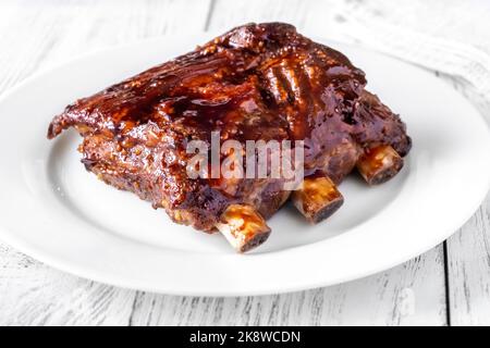 Côtelettes de porc au barbecue sur la plaque blanche Banque D'Images