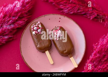 Crème glacée au cupcake avec crème au chocolat.Cupcakes au chocolat sur une assiette rose avec des fleurs séchées roses sur un fond de fuchsia brillant.chocolat Banque D'Images