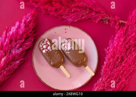 Crème glacée à base de cupcake et crème au chocolat.des cupcakes au chocolat sont préparés sur une assiette avec des fleurs séchées sur un fond de fuchsia.vue d'en haut.chocolat Banque D'Images