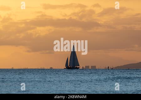 Superbe coucher de soleil au départ d'Oahu à Hawaï avec silhouettes de surfeurs et nageurs. Banque D'Images