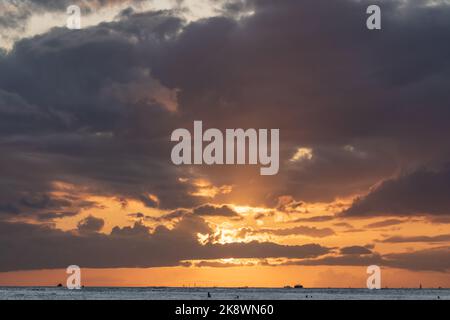 Superbe coucher de soleil au départ d'Oahu à Hawaï avec silhouettes de surfeurs et nageurs. Banque D'Images