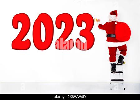 Le Père noël tire le rouge de la nouvelle année 2023 sur le mur blanc Banque D'Images