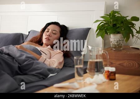 Une jeune femme malade dormant au lit après avoir pris des médicaments Banque D'Images