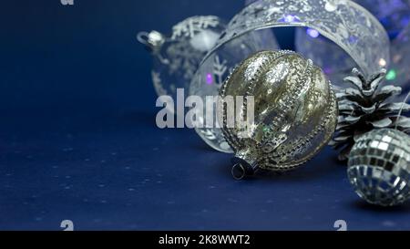 superbes boules de noël argentées scintillantes sur fond bleu foncé. Banque D'Images