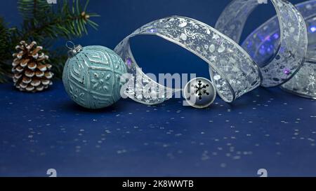 boules de noël et ruban de curling argenté sur fond bleu Banque D'Images