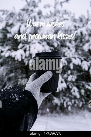 Voeux chaleureux et bonhomme de neige inspiration blague citation phrase main féminine en hiver gants chauds tenant une tasse en papier écologique noir. Tasse de recyclage tendance sans déchets créative. Boisson chaude à aller en hiver vertical Banque D'Images