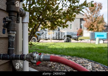 Hivernage d'un système d'irrigation résidentiel à l'aide d'un compresseur et d'air forcé pour souffler les conduites vides. Banque D'Images