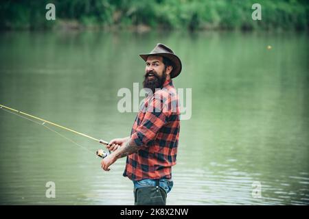 Pêcheur utilisant la pêche à la perche dans la rivière de montagne. Un pêcheur de mouche pêche à la truite sauvage sur la rivière dans la forêt. Banque D'Images