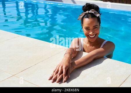 Le bonheur est une journée à la piscine. Une belle jeune femme qui se détend dans une piscine. Banque D'Images