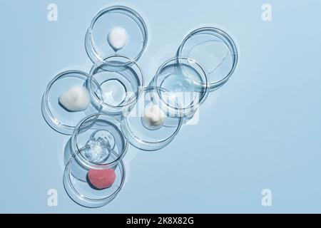 De nombreuses boîtes de Petri et différents échantillons de produits cosmétiques sur fond bleu, à plat. Espace pour le texte Banque D'Images