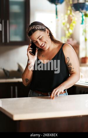 J'aime aussi le son de votre voix... une jeune femme qui utilise un smartphone dans la cuisine à la maison. Banque D'Images