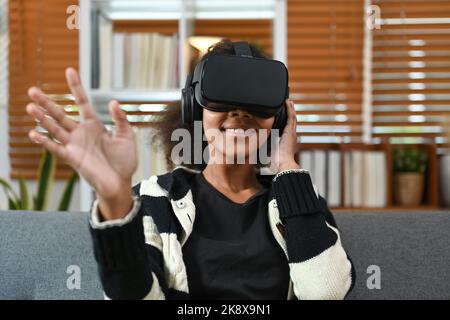 Femme enthousiaste et adolescente qui vit des opportunités de jeu dans un micro-casque de réalité virtuelle. Concept de technologie futuriste Banque D'Images