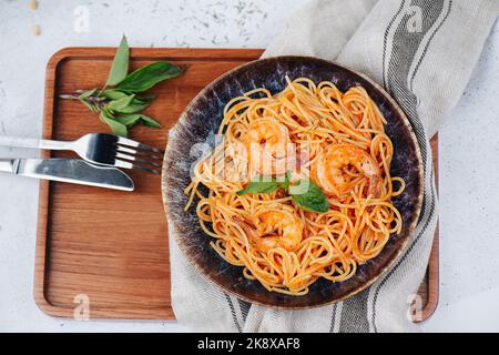 Vue en hauteur sur les pâtes d'orange avec crevettes et sauce dans une assiette sur une table. Banque D'Images